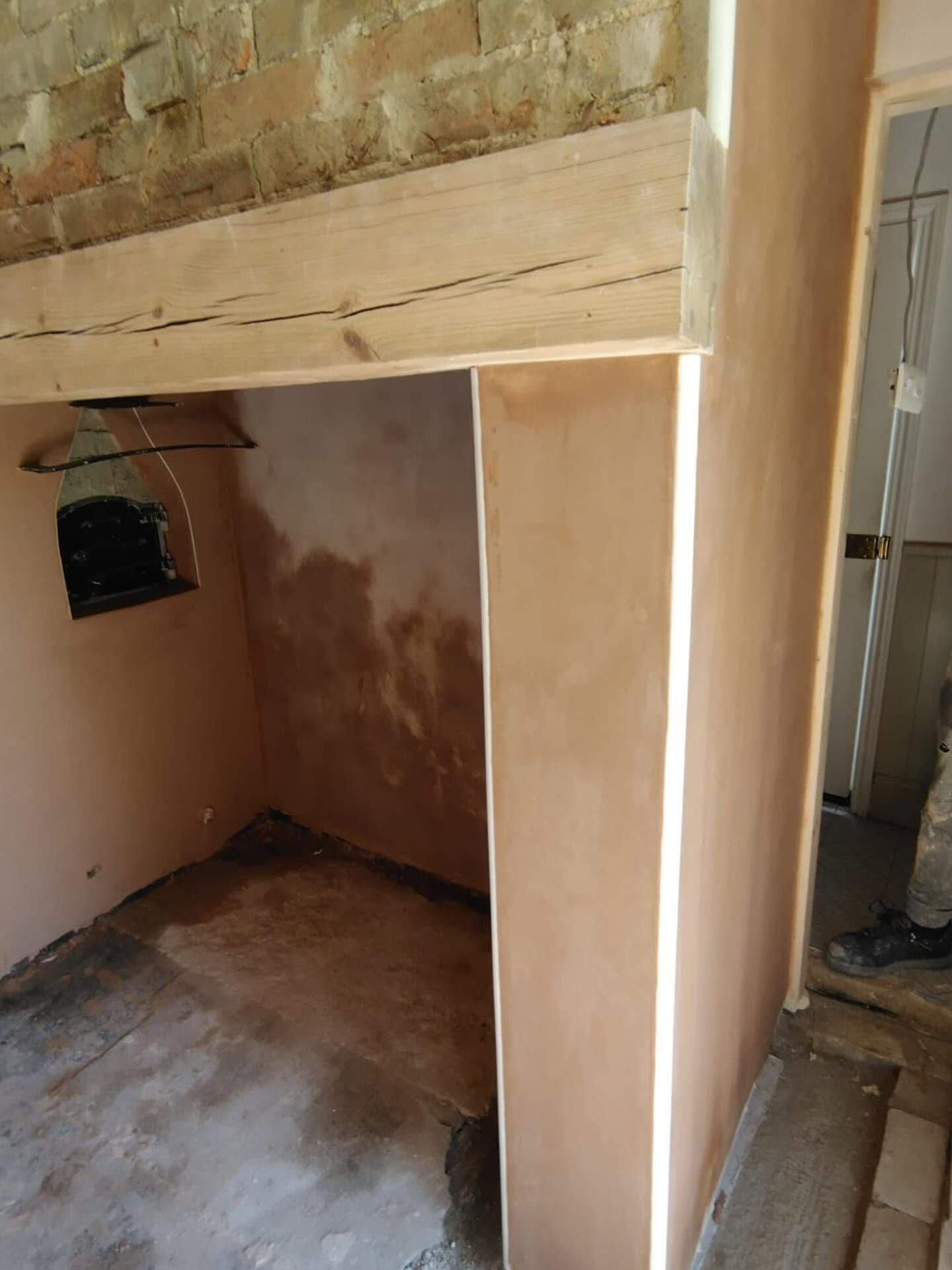 Fireplace with an oak beam and freshly plastered reveals