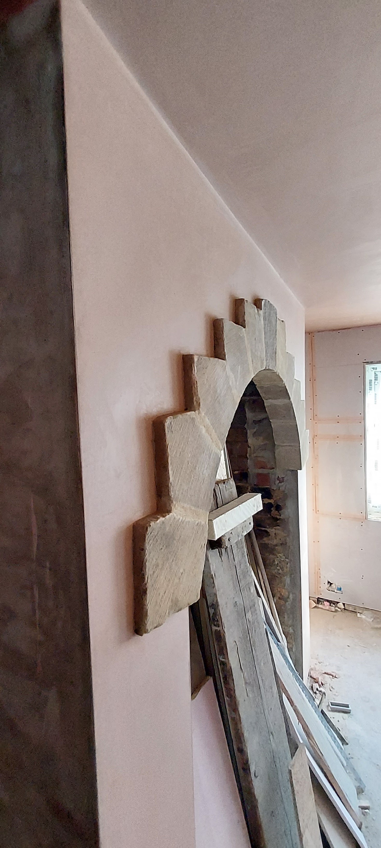 Fresh plaster finished neatly against a stone arch